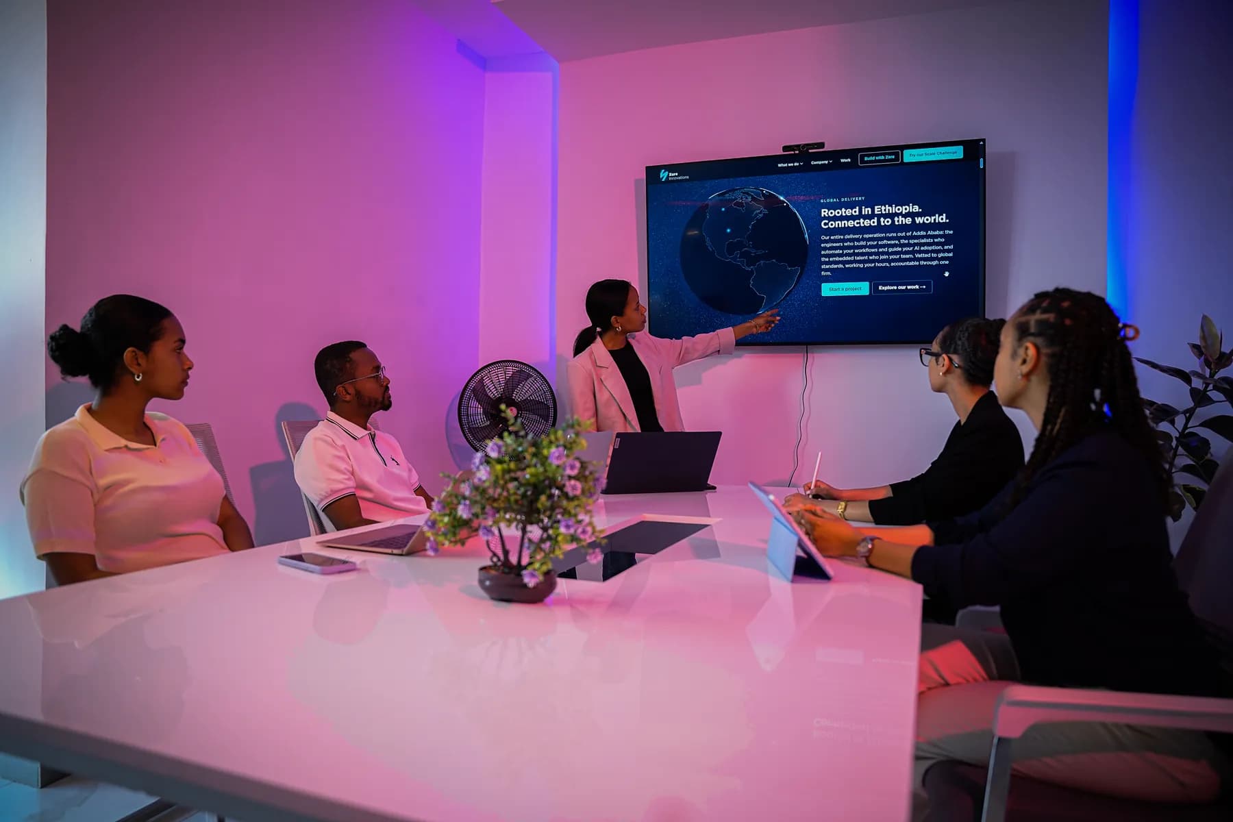 A Zare team member presenting to colleagues around the meeting-room table