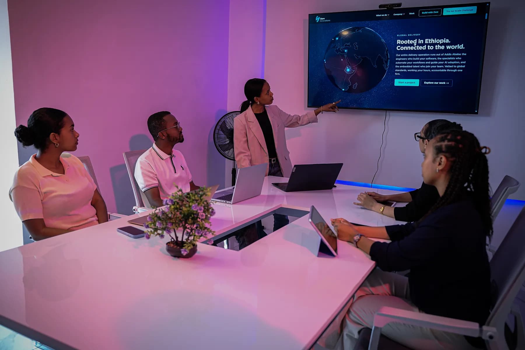 A Zare team member walking colleagues through delivered work on the meeting-room screen