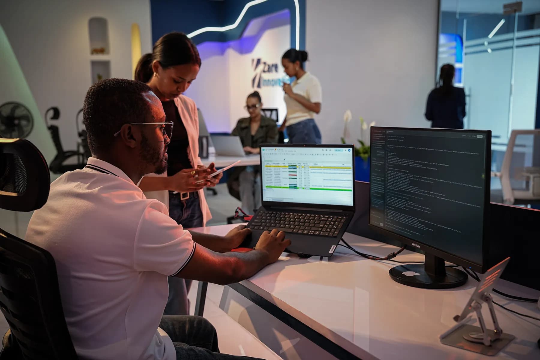 A Zare engineer writing code across a laptop and an external monitor